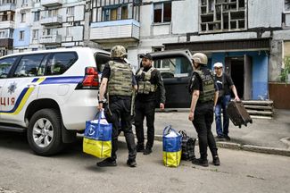 Сотрудники полиции помогают эвакуироваться семье, которая жила рядом с разрушенным в результате российского удара многоквартирным домом. 21 мая 2024 года