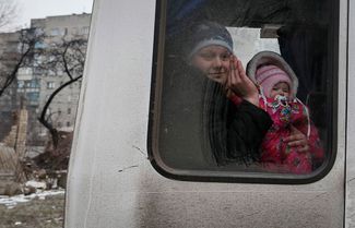 A woman and a child look through a bus window before leaving as people flee the conflict in Debaltseve, February 5, 2015.