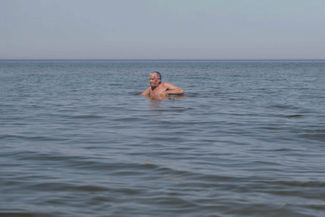 Ernests Šliseris checks his fishing nets across from his home. In the 1930s, this was still dry land. July 2024.