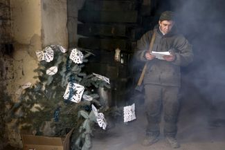 Военнослужащий Народной милиции самопровозглашенной ДНР читает письмо у новогодней елки недалеко от линии фронта