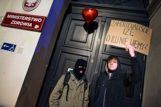 Протестующие у входа в здание Минздрава Польши с плакатом: «Вы убили Изу. О скольких еще мы пока не знаем?». Варшава, 6 ноября 2021 года
