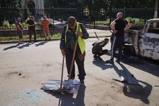 A utility worker removes debris from a downed Russian drone, May 22, 2026.