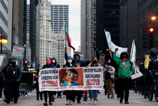 Демонстранты с плакатами на акции протеста против убийства 13-летнего Адама Толедо. Чикаго, 14 апреля 2021 года