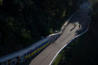 Велосипедист с украинским флагом проезжает мимо надписи «Независимость» на украинском языке
