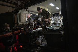 Украинские военные врачи переносят раненого солдата из медпункта в автомобиль перед эвакуацией с передовой под Авдеевкой. Российская армия начала наступление на пригород оккупированного Донецка в конце 2023 года