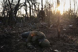 Командир подразделения 3-й штурмовой бригады проходит мимо тела убитого российского солдата в нескольких километрах от Андреевки 
