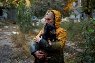 Жительница Николаева держит на руках свою собаку, стоя возле поврежденного российскими обстрелами здания. Николаев подвергается регулярным обстрелам, под удар <a href="https://t.me/uniannet/75984" rel="noopener noreferrer" target="_blank">попадают</a> и жилые дома