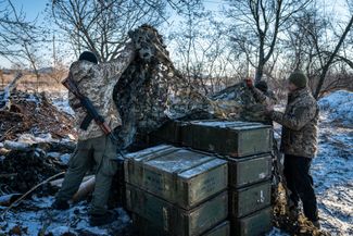 Бойцы ВСУ снимают маскировочную сетку с ящиков с боеприпасами
