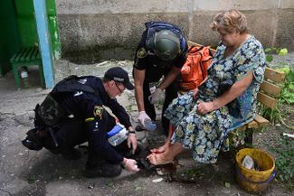 Полицейские оказывают первую помощь жительнице Краматорска, пострадавшей от российского ракетного обстрела