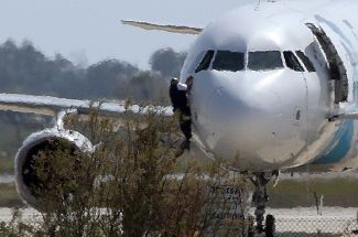 Мужчина вылезает из кабины пилотов лайнера EgyptAir. Кипр, Ларнака, 29 марта 2016 года