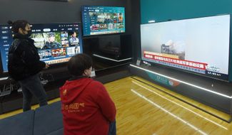 Посетители торгового центра в городе Ханчжоу на востоке Китая смотрят новости о войне в Украине. 25 февраля 2022 года