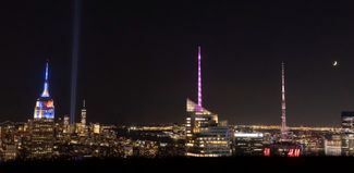 Световая инсталляция «Дань памяти в свете» (слева) со смотровой площадки на 70-м этаже Рокфеллер-центра в Нью-Йорке. Лучи высотой более шести километров сформированы светом 88 прожекторов, которые находятся недалеко от места, где раньше были башни Всемирного торгового центра.
