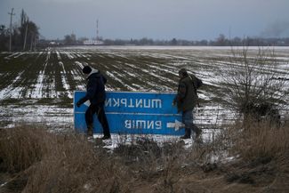 Бойцы теробороны в Киевской области уносят с дороги знак, чтобы российские войска не могли сориентироваться на местности. 8 марта 2022 года