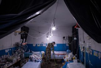 Украинский военный медик моет пол в небольшой операционной в прифронтовом полевом госпитале в городе Попасная, Луганская область