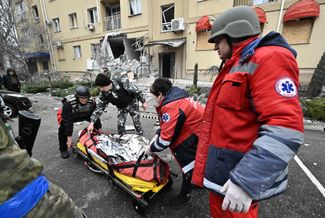 Украинские врачи несут тело погибшего во время обстрела