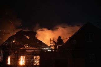 Пожарные тушат огонь в домах, разрушенных в результате обстрела Донецка