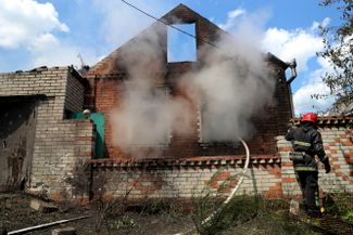 Пожарный на окраине Харькова тушит огонь в здании, пострадавшем после обстрела.