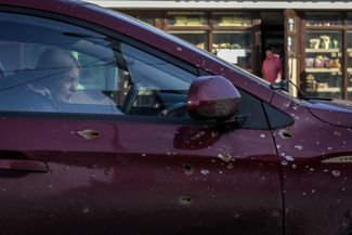 Жительница Бахмута в машине, на которой видны следы от осколков