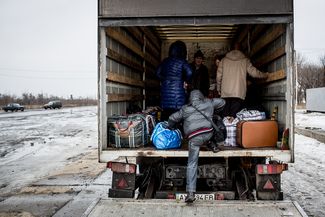 A man jumps on a large lorry carrying evacuees fleeing from the increasing battles between pro-Russian separatists and the Ukrainian army, 31 January 2015.