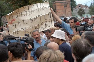 Родные и близкие заложников с плакатом «Путин!!! В заложниках находится не меньше 800 человек!» у здания школы, 2 сентября 2004 года. Изначально власти занижали данные о количестве заложников в школе