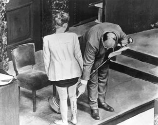 Бывшая заключенная концлагеря демонстрирует шрамы, оставшиеся после медицинских экспериментов, во время Нюрнбергского процесса. 22 декабря 1946 года