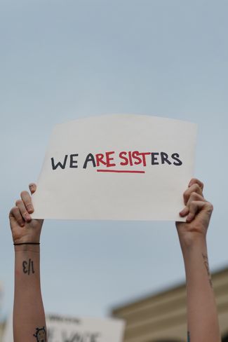 Участница протестов в Атланте, штат Джорджия, держит плакат: «Мы сестры», буквы складываются в слово resist — «сопротивляться»