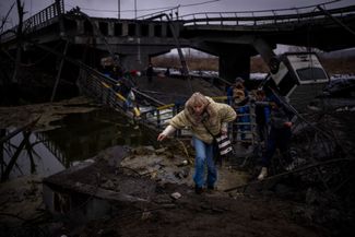 Женщина переходит через разрушенный после российского авиаудара мост на окраине Киева. 2 марта 2022 года