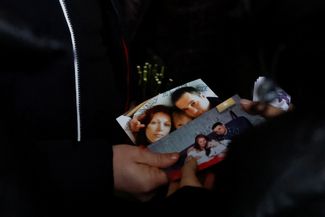 Люди смотрят семейные фотографии Кореновских во время похорон 