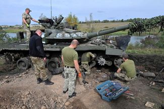 Бойцы ВСУ осматривают танк, брошенный отступающими российскими военными к северу от Харькова