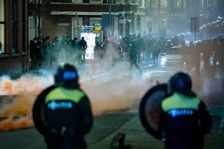 Группа молодых людей бросает камни и фейерверки в полицейских в Роттердаме, 25 января 2021 года