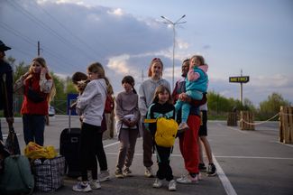Семья, прибывшая на машине из оккупированного Россией города Токмак, в ожидании гуманитарного конвоя в пункте регистрации беженцев в Запорожье.