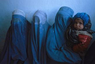 Женщины, одетые в традиционную для Афганистана голубую бурку, ждут своей очереди на диагностику и лечение в клинике в Пагмане, Афганистан.