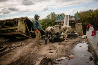 Украинские солдаты убирают куски металла с моста через Северский Донец в освобожденном Изюме