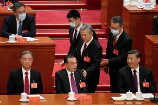 Бывшего председателя КНР Ху Цзиньтао выводят из зала заседания во время пленума компартии в Пекине. 22 октября 2022 года