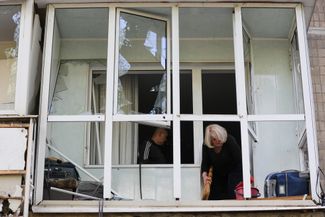 Жительница Донецка убирает с балкона стекла, разбитые в результате обстрела. 21 мая 2024 года