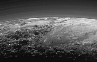 На этой фотографии запечатлена Равнина Спутник (справа), которая перетекает в горы Норгея высотой до трех с половиной тысяч метров. Кроме того, здесь из-за специфического освещения Солнцем видны слои атмосферы Плутона.