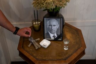 Инсталляция с портретом Владимира Путина у входа в один из ресторанов в Киеве. Посетитель ресторана вставляет в куклу типа вуду булавку