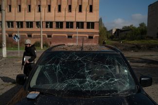 Украинский полицейский идет мимо машины, поврежденной при российском наступлении в Краматорске, который сейчас находится под контролем ВСУ