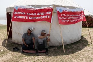 Participants in the “indefinite rally” in defense of the Kempir-Abad reservoir sit behind a yurt to escape the sun near Kyzyl-Oktyabr. April 23, 2021.