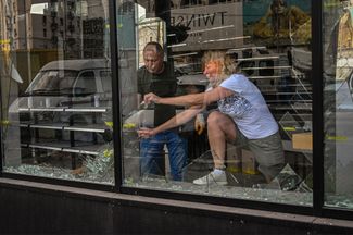 Харьковчане убирают разбитое стекло из витрины магазина в центре города