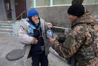Украинский военный передает воду жительнице Бахмута