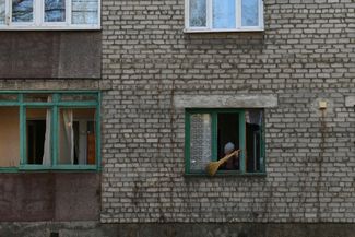 Жительница Донецка смахивает с подоконника разбитое стекло