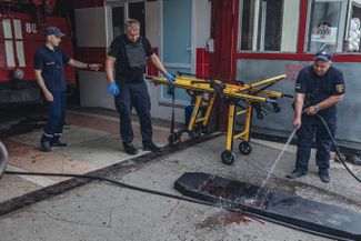 Сотрудники ГСЧС Украины смывают кровь с носилок, на которых транспортировали раненого жителя Бахмута