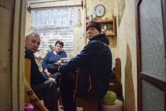 Serhii (left), Lyuda, and Ruslan sit in the small kitchen of the apartment they share. Kostiantynivka, November 2023.