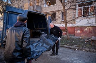 Utility workers carry the body of the deceased resident of Kramatorsk from the site of a missile attack