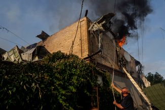 Житель Херсона вместе с пожарным тушит горящий дом, который пострадал в результате российского обстрела 