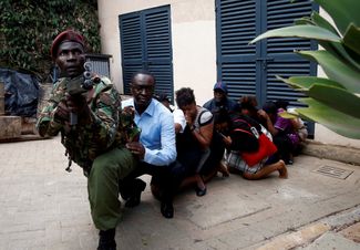 Сотрудник сил безопасности занимается эвакуацией людей во время атаки террористов на отель Dusit в Найроби, Кения. 15 января 2019 года