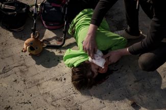 Харьковчанка, пострадавшая во время российской атаки, ждет прибытия «скорой помощи» в городском парке.