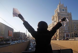 A woman waves a white sheet of paper and a white ribbon at drivers on Moscow’s Garden Ring. This photo was taken on January 29. At the time, hundreds of cars with white ribbons or white balloons were circling the Garden Ring in a show of support for the protesters.