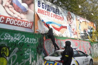Украинские полицейские снимают пророссийские билборды на одной из улиц освобожденного Херсона. 16 ноября 2022 года